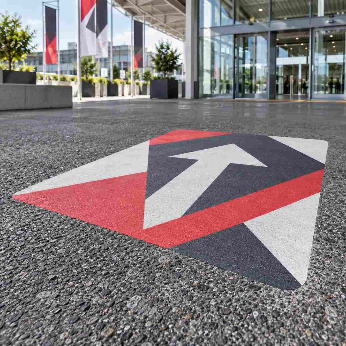 Vinilo impreso personalizado aplicado sobre suelo rugoso de asfalto en un acceso exterior